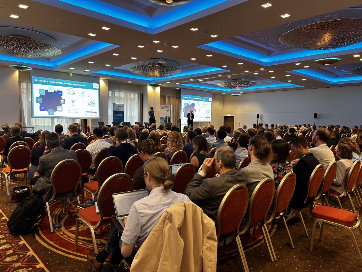 Foto taken from the back of the room showing two speakers at the podium and the audience.